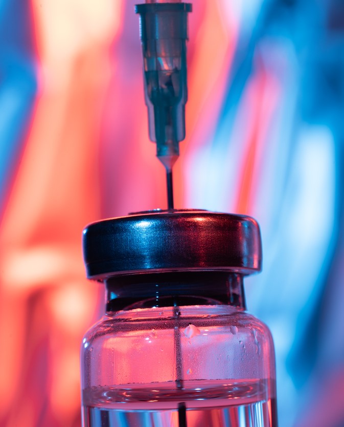 Close-up of needle inserted into vaccine vial