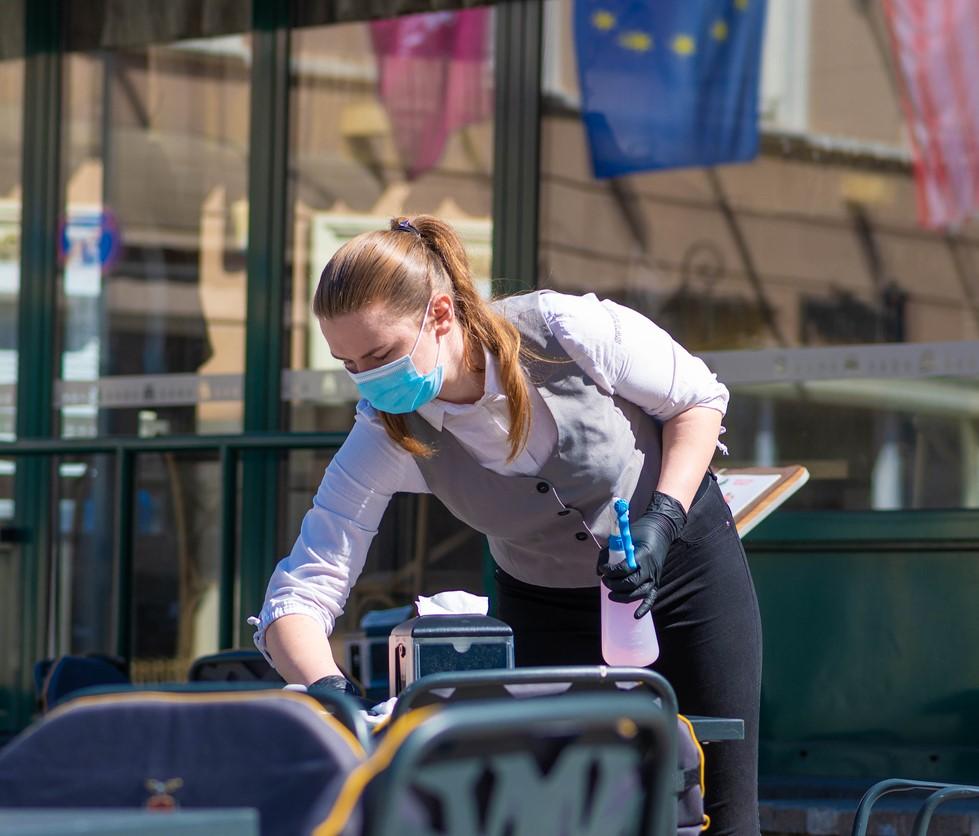 Lithuanian waitress disinfecting tables outdoors