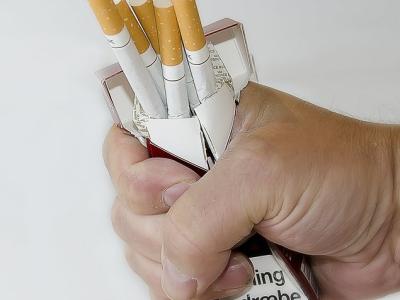 Hand crushing a pack of cigarettes