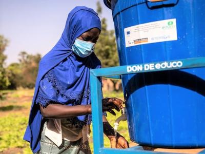 Girl wearing mask in Africa washing hands