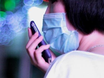 Woman with cell phone and surgical mask