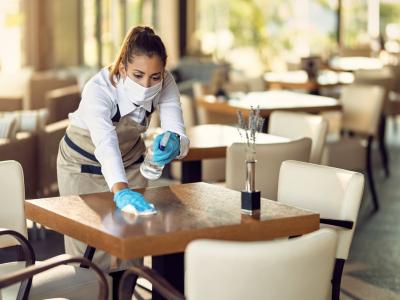 Masked waitress cleaning table