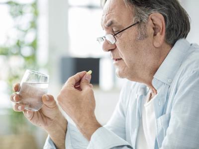 Older man taking white pill