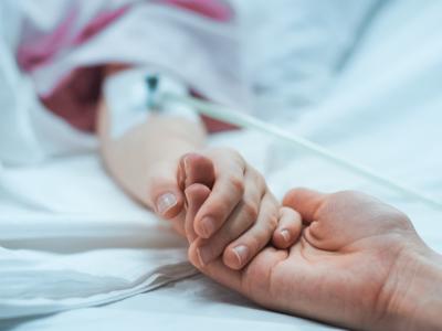 Parent holding child's hand in hospital