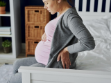Pregnant woman sitting on bed